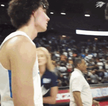 a man in a white tank top is standing in front of a crowd with a thunder logo on his chest