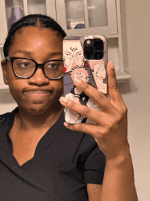 a woman wearing glasses takes a selfie with a phone case that has a cartoon character on it