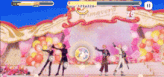 a group of people are dancing on a stage with balloons in the background .