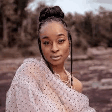 a woman with braids is wearing a polka dot dress and a bun .