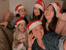 a group of women wearing santa hats are posing for a photo