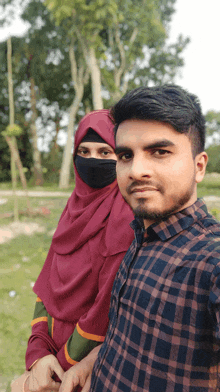 a man and a woman pose for a picture with the woman wearing a hijab