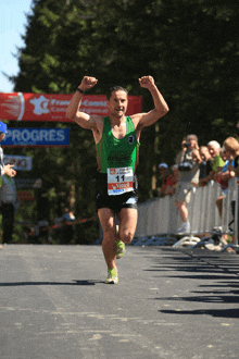 a man in a green tank top is running in front of a sign that says progress