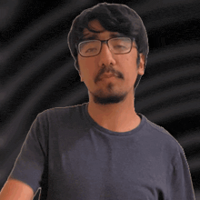 a man with glasses and a beard is wearing a blue t-shirt