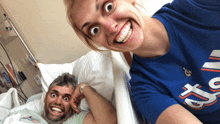 a man in a hospital bed with a woman wearing a blue shirt that says t2