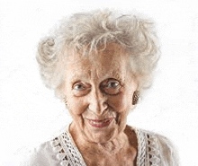 an elderly woman with white hair is smiling for the camera .