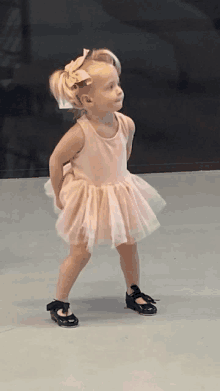 a little girl in a pink dress and black shoes is dancing