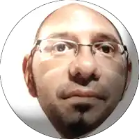 a man with glasses and a beard looks at the camera