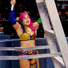 a female wrestler with pink hair is holding a microphone in front of a ladder