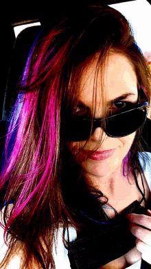 a woman wearing sunglasses has purple and pink hair