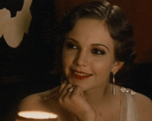 a woman in a white dress is smiling and applying makeup