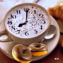 a cup of coffee with a clock on it and two chocolate donuts next to it