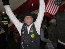 a man wearing a cowboy hat and a sheriff 's vest is holding an american flag