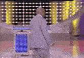 a bald man in a suit is standing in front of a blue light
