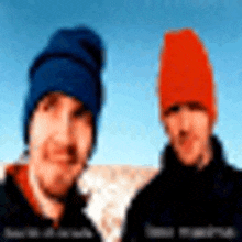 two men wearing beanies are posing for a picture