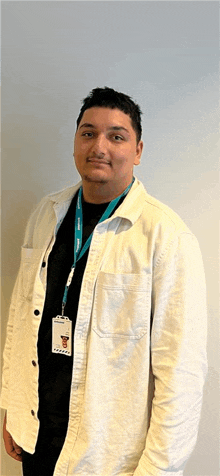 a man wearing a lanyard with a name tag that says ' a ' on it stands in front of a white wall