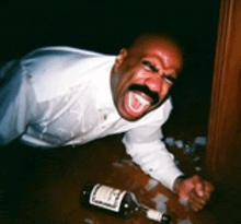 a man with a mustache is laying on the floor with a bottle of wine in front of him