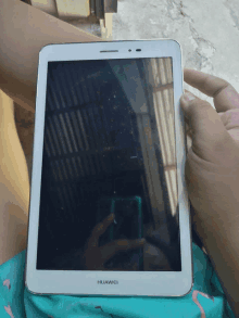 a person holding a huawei tablet in their hand