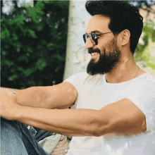 a bearded man wearing sunglasses and a white shirt