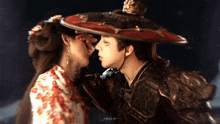 a man and a woman are kissing and the man is wearing a hat and armor .