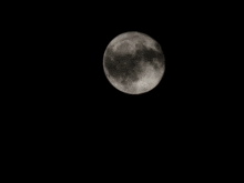 a full moon in the night sky with a black background