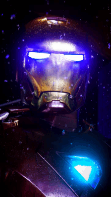 a close up of iron man 's helmet with a blue light behind it