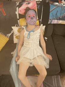 a little girl laying on a couch with face paint