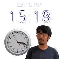 a man with glasses stands in front of a clock that reads 15:18