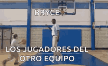 a man is playing basketball in a gym with the words bryce los jugadores del otro equipo written above him .