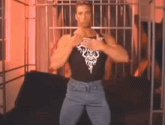 a man wearing a black tank top and jeans is standing in front of a couch .