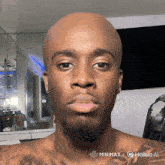 a man with a beard and a bald head is looking at the camera with a hailuo ai logo in the corner
