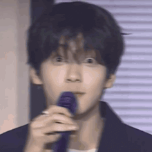 a young man is holding a purple microphone in his mouth .