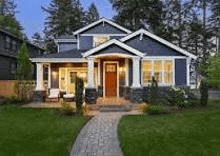 a large blue house with a brick walkway leading to the front door .