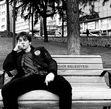 a young man is sitting on a bench that says ehir belediyesi on it