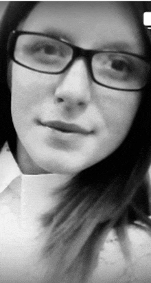 a black and white photo of a woman wearing glasses and a white shirt