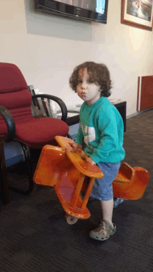 a young boy in a green sweater is playing with a rocking horse toy