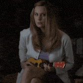 a woman holding a guitar with the name olivia wilde on the bottom right