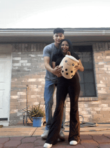 a man and a woman holding a stuffed bubble tea cup in front of a brick building