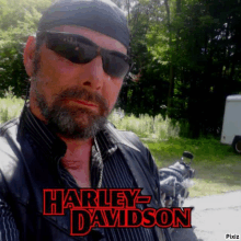 a man with a beard wearing sunglasses and a harley davidson vest