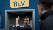 a man with a mustache points to a sign that says blv