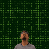a man with a beard stands in front of a green background with the number 21 on it