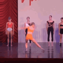 a group of young women are dancing on a stage with a red curtain behind them and a sign that says 7