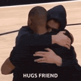 two men are hugging each other on a basketball court and the words `` hugs friend '' are visible .