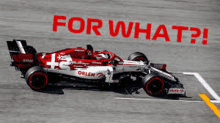 a red and white race car is driving down a track with the words `` for what ? '' written on it .