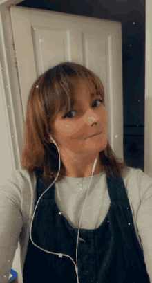 a woman wearing headphones is taking a selfie in front of a door