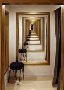 a dressing room with a long hallway of mirrors and stools .