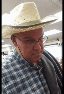 a man wearing a cowboy hat and glasses looks at the camera