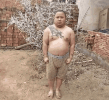 a shirtless man with a dragon tattoo on his arm stands in front of a brick wall