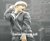 a young man in a black hoodie is dancing on a stage in front of a crowd .