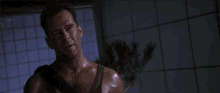 a man in a tank top is standing in front of a tiled wall and says well , well , well .